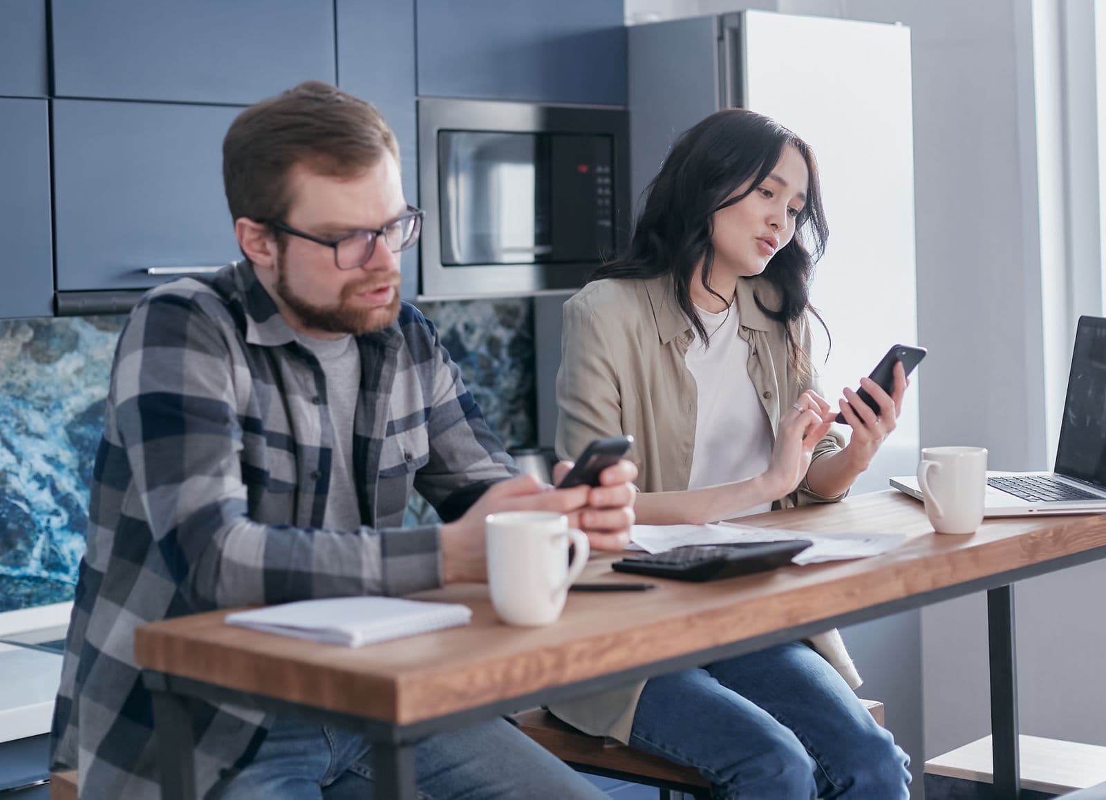 A couple planning payments with a phone and laptop