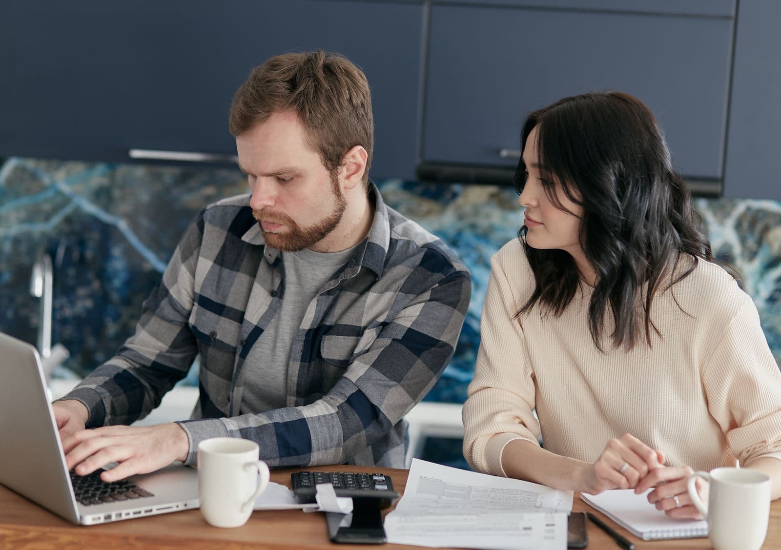 Two people comparing information on a laptop